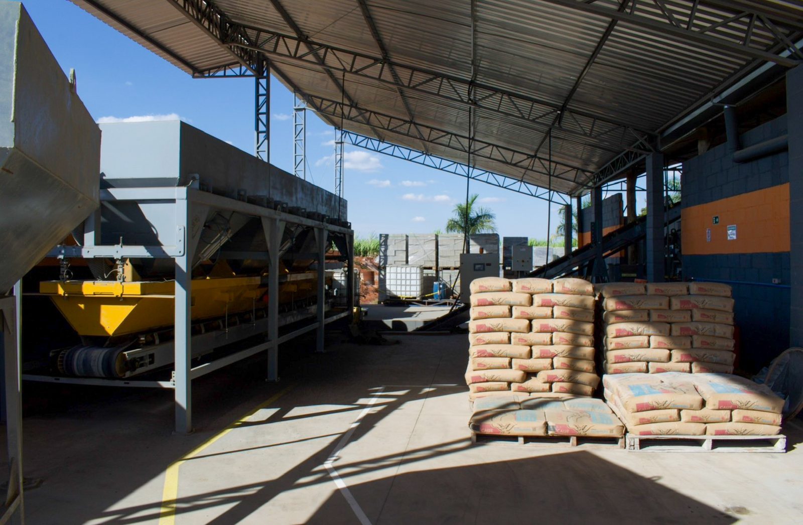 Área de produção com esteira de agregados e estoque de cimento
